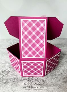 a pink and white box sitting on top of a cement surface with the lid open