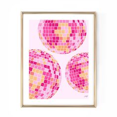 three pink and yellow squares on a white background in a gold frame, hanging on the wall