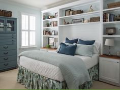 a bed sitting in a bedroom next to a book shelf filled with lots of books