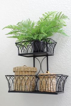 two black metal shelves with baskets and plants on them