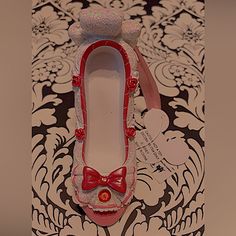 a pair of red shoes with bows on them sitting on top of a floral wallpaper