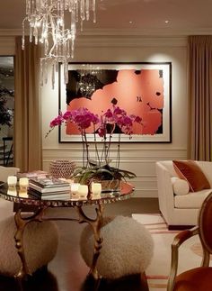 a living room filled with furniture and a chandelier above a glass top table