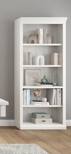 a white book shelf with books and other items on it in the corner of a room