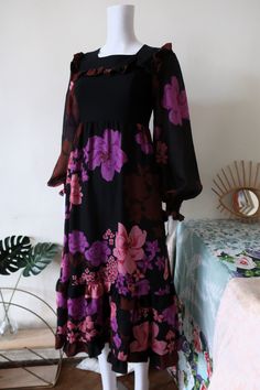 Stunning True Vintage 1970s maxi dress from Finnish designer Heikkilä. Fit and flare cut. Light and comfortable fabric with beautiful large dark floral print in purple, pink and brown tones. Top with square neck, fitted black bodice, ruffle bib and yoke. Wide long sleeves, semi sheer with elasticated cuffs. Wide skirt with ruffle hem. Zipper in the back. Lined except the sleeves. Made in Finland! BRAND: Heikkilä ERA: 1970s COLOR: Black, purple, pink, brown, red Fabric: 100% cotton, 100% polyester SIZE: Vintage size 34, fits best size XXS-XS - please check the measurements below for reference MEASUREMENTS: Pit to pit 38cm, single wast 33cm, total length 118cm CONDITION: Very good Vintage condition Retro Floral Print Maxi Dress For Fall, Bohemian Purple Maxi Dress With Ruffles, Purple Long Sleeve Maxi Dress With Ruffles, Purple Floral Print Maxi Dress, Purple Long Sleeve Ruffled Maxi Dress, Vintage Black Maxi Dress With Floral Print, Vintage Purple Maxi Dress, Skirt With Ruffle Hem, Dark Floral Print