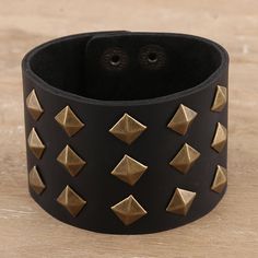 Golden studs gleam in the light, giving Deepika Lohani's cuff bracelet a touch of luxury. Indian artisans hand craft the bracelet from a wide strip of black leather, embellishing the cuff with brass-plated iron studs. Two row of brass-plated iron snap buttons let you adjust the size to fit your wrist. Black Leather Bracelets With Studs, Black Studded Bracelets For Party, Black Bracelets With Rivets As Gift, Adjustable Black Studs Jewelry, Black Adjustable Studded Wristband, Adjustable Black Studded Wristband, Adjustable Black Cuff Bracelet With Rivets, Black Leather Jewelry With Studs, Adjustable Cuff Bracelet With Rivets As Gift