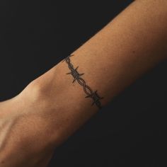 a person with a tattoo on their arm that has barbed wire in the shape of a cross