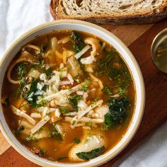 a white bowl filled with soup next to a slice of bread on top of a wooden cutting board