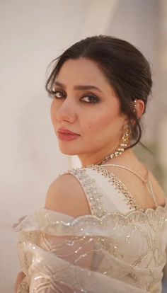 a woman in a white dress with pearls on her neck and shoulder, wearing large earrings