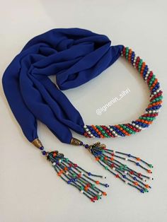 a blue scarf with multi colored beads and tassels on the end of it