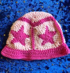 a crocheted pink and white hat sitting on top of a blue blanket