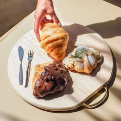 a person reaching for a pastry on a plate with utensils and spoons