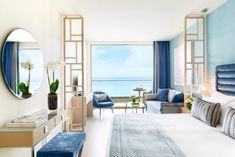 a bedroom with blue and white decor on the walls, along with an ocean view