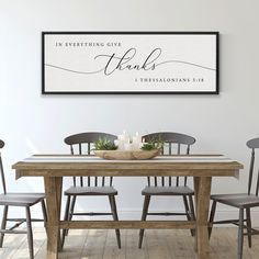 two framed pictures on the wall above a dining room table with chairs and a candle