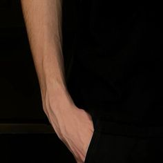 a close up of a person's hand holding something in their left hand and wearing a black shirt