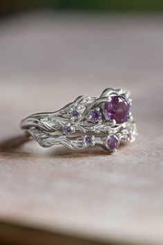 a close up view of a ring with purple stones in it on top of a table