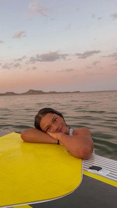 a woman laying on top of a yellow surfboard