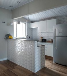 a kitchen with white walls and wooden floors has an island in the middle that is made out of metal