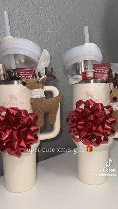 two coffee mugs decorated with bows and reindeer decorations are sitting on a counter next to each other