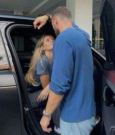 a man standing next to a woman getting out of a car with the door open