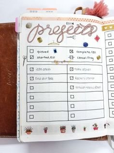 an open planner is sitting on top of a leather book with the words progress written in cursive writing