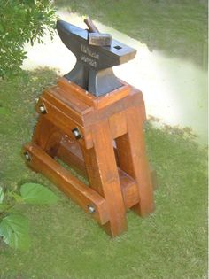 an old style hammer is sitting in the grass next to a wooden stand that has been placed on top of it