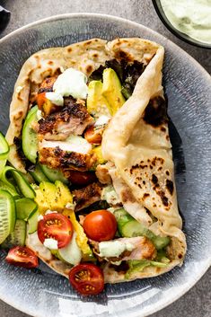 two pita sandwiches on a plate with cucumbers, tomatoes and other vegetables