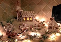 a group of gingerbread houses sitting on top of snow covered ground next to christmas lights