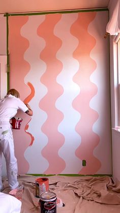 a person painting a wall with pink and white waves on it in a room that is being renovated