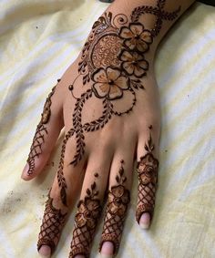 a woman's hand with hennap and flowers on the top of it