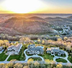 an aerial view of houses in the mountains at sunset or sunrise with trees and grass