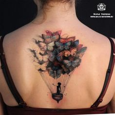 the back of a woman's shoulder with butterflies and a person holding a kite