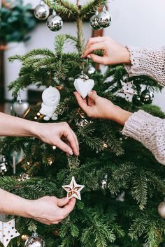 two women decorating a christmas tree with ornaments on the top and one holding a star ornament