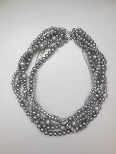 1 - 7 strand different shades of grey pearl Rhinestone and chain beaded necklace.   Pearl braided twisted beaded necklace 18 - 21 inches. Necklace has a lobster claw clasp, and 3 inch extender chain.  They are glass pearl beads. Love this necklace so much, wear it with tee and jeans or dress it up. Also great for bridesmaids! I can do a bracelet and earrings to match.  Please let me know if you have any question about the necklaces. I can do this necklaces in different color pearls and amount of strands. See last picture for colors, they range from pale pink/blush, white, ivory/cream, champagne/tan, light gray and dark gray, black and navy. I also have many other colors and can get other colors too.  There are many colors I can get too.  I can also send you pic of other necklaces I did for Statement Pearl Necklace, Bridesmaid Pearl Bracelet, Grey Pearl Necklace, Swarovski Pendant, Pearl Statement Necklace, Bridal Pearl Necklace, Bridesmaid Pearls, White Pearl Earring, Silver Pearl Necklace