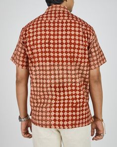 a man wearing an orange and white patterned shirt with his back turned to the camera