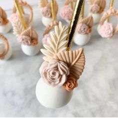 there are many small white vases with flowers in them on the marble counter top