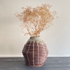 a vase with some plants in it on top of a table next to a wall