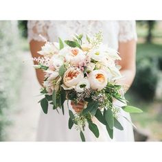 a woman holding a bouquet of flowers in her hands and wearing a white wedding dress