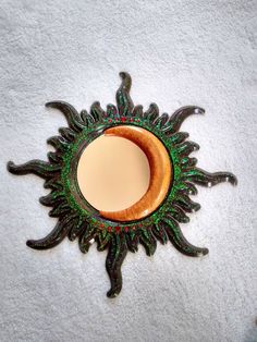 a decorative mirror on the wall with an orange and green decoration around it's edge