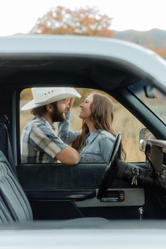 a man and woman sitting in the driver's seat of a pick up truck