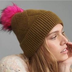 a woman wearing a brown hat with pink fur pom - pom on it