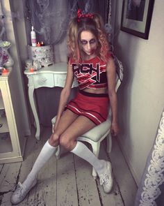 a woman dressed as a cheerleader sitting on a chair in front of a mirror