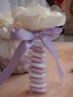 a vase filled with flowers and ribbons on top of a wooden table next to a pillow