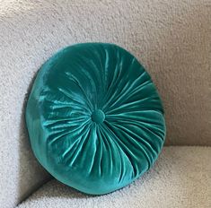 a green round pillow sitting on top of a white couch