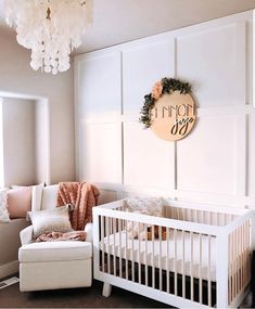 a baby's room with a crib, chair and chandelier