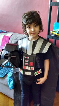 a young boy dressed as darth vader from star wars standing in front of a couch