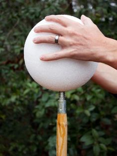 a person's hand on top of a white ball with a wooden stick sticking out of it