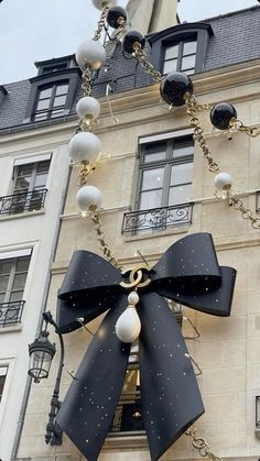 a large black and white bow hanging from the side of a building with lights on it