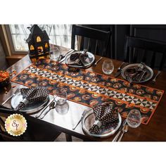 the table is set for halloween dinner with black and orange placemats, silverware, and candy