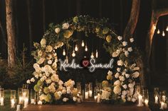 an outdoor wedding ceremony with candles and flowers on the aisle, surrounded by tall trees