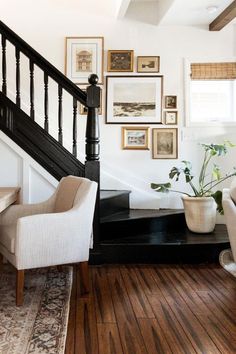 a living room filled with furniture and pictures on the wall next to a stair case